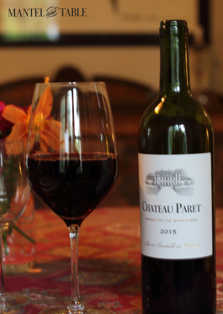 Chateau Paret bottle with glass of pizza wine and orange flower behind.