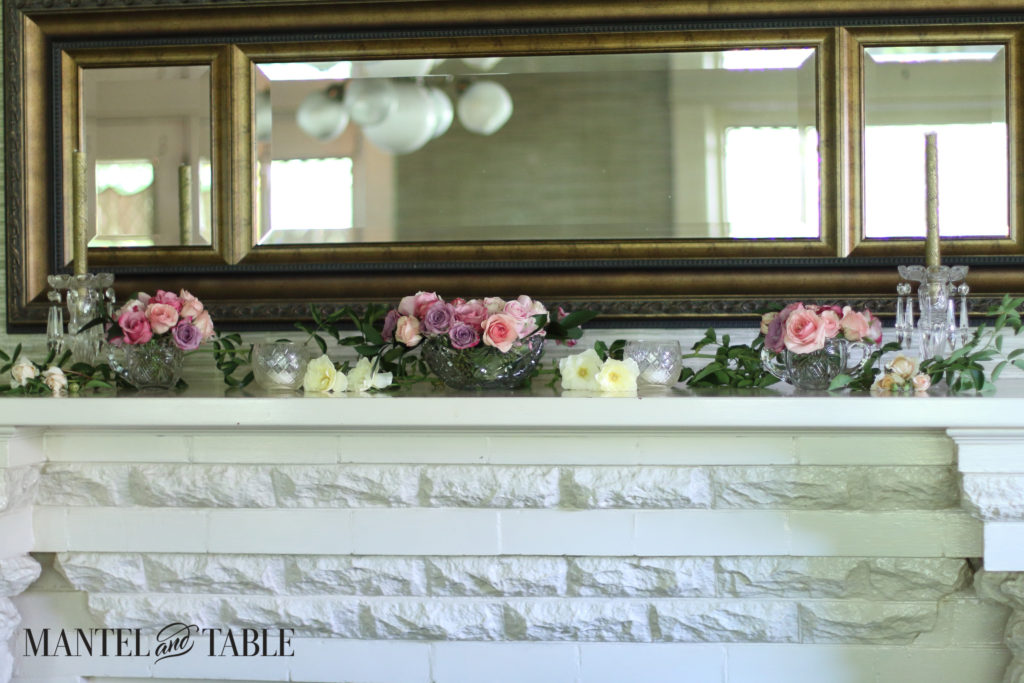 Beautiful wood and gold leaf horizontal mirror over the mantel with roses in front.