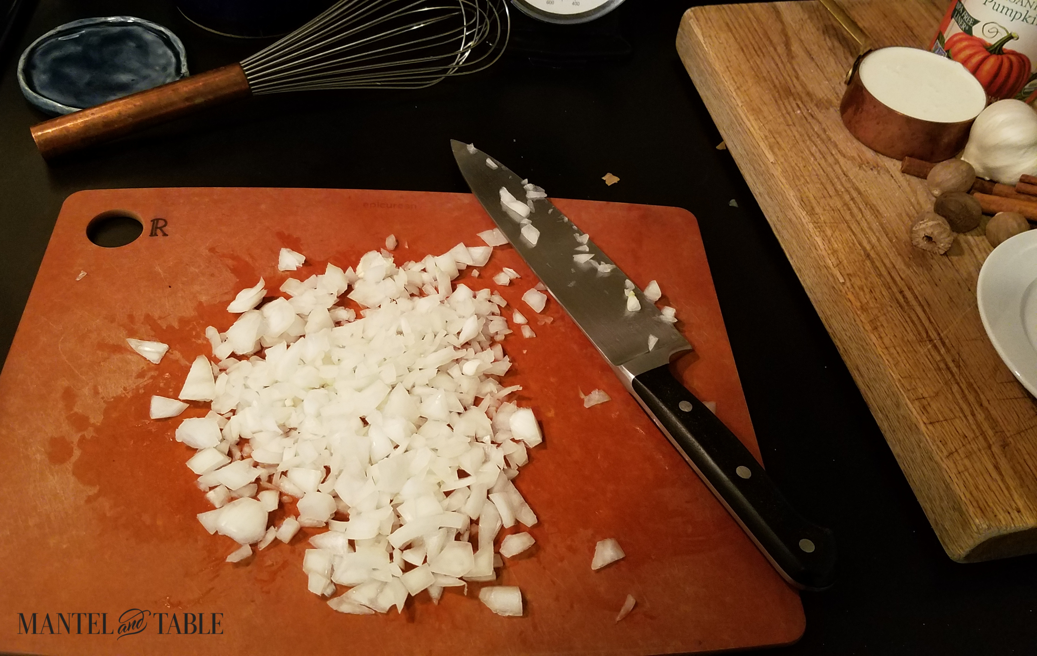 A pile of chopped onion on the cutting board, with knife.