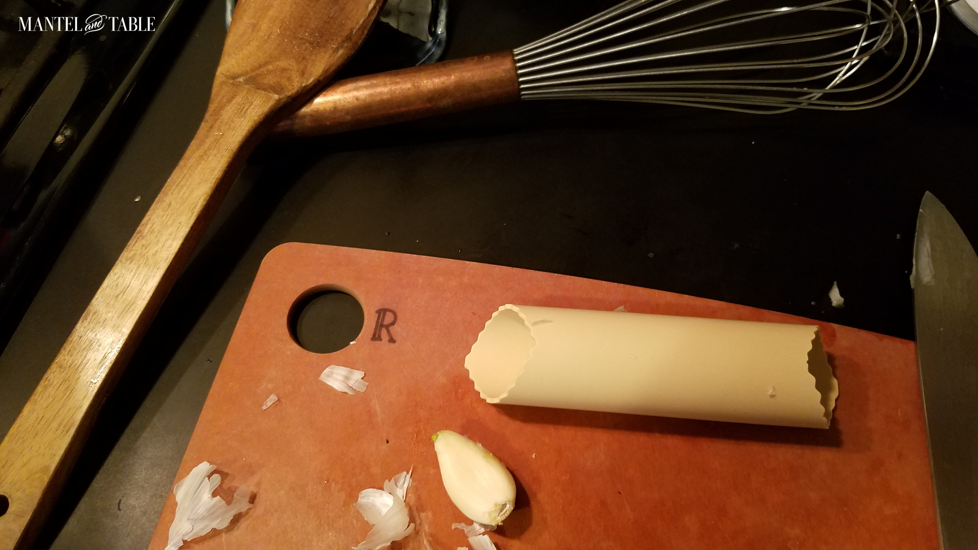 Garlic clove on the cutting board, with silicone garlic peeler tube.