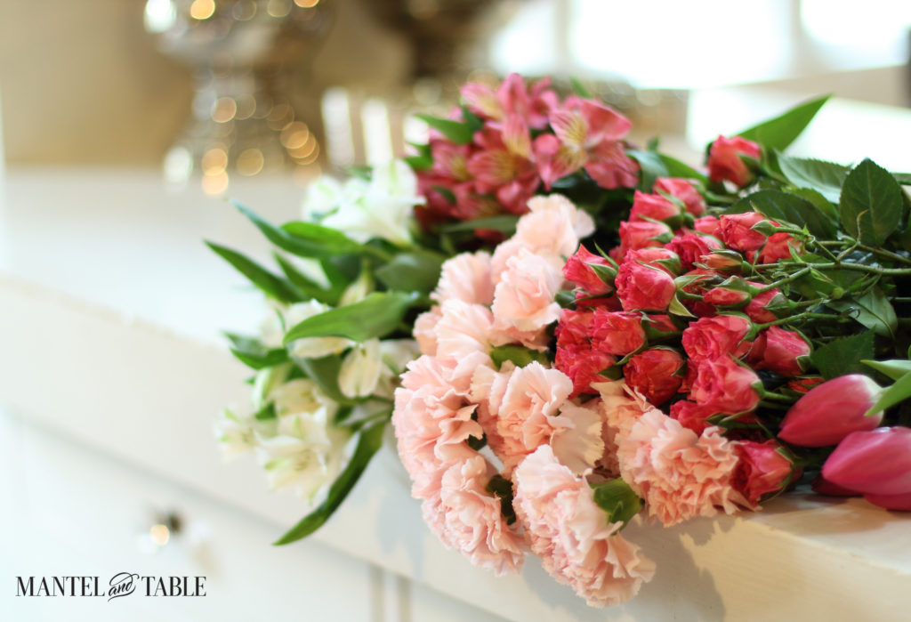 failure-learn-from-organization-disaster - Bunches of white & pink flowers draping over the white sideboard. Soft focus silver urn and mirror in the background.