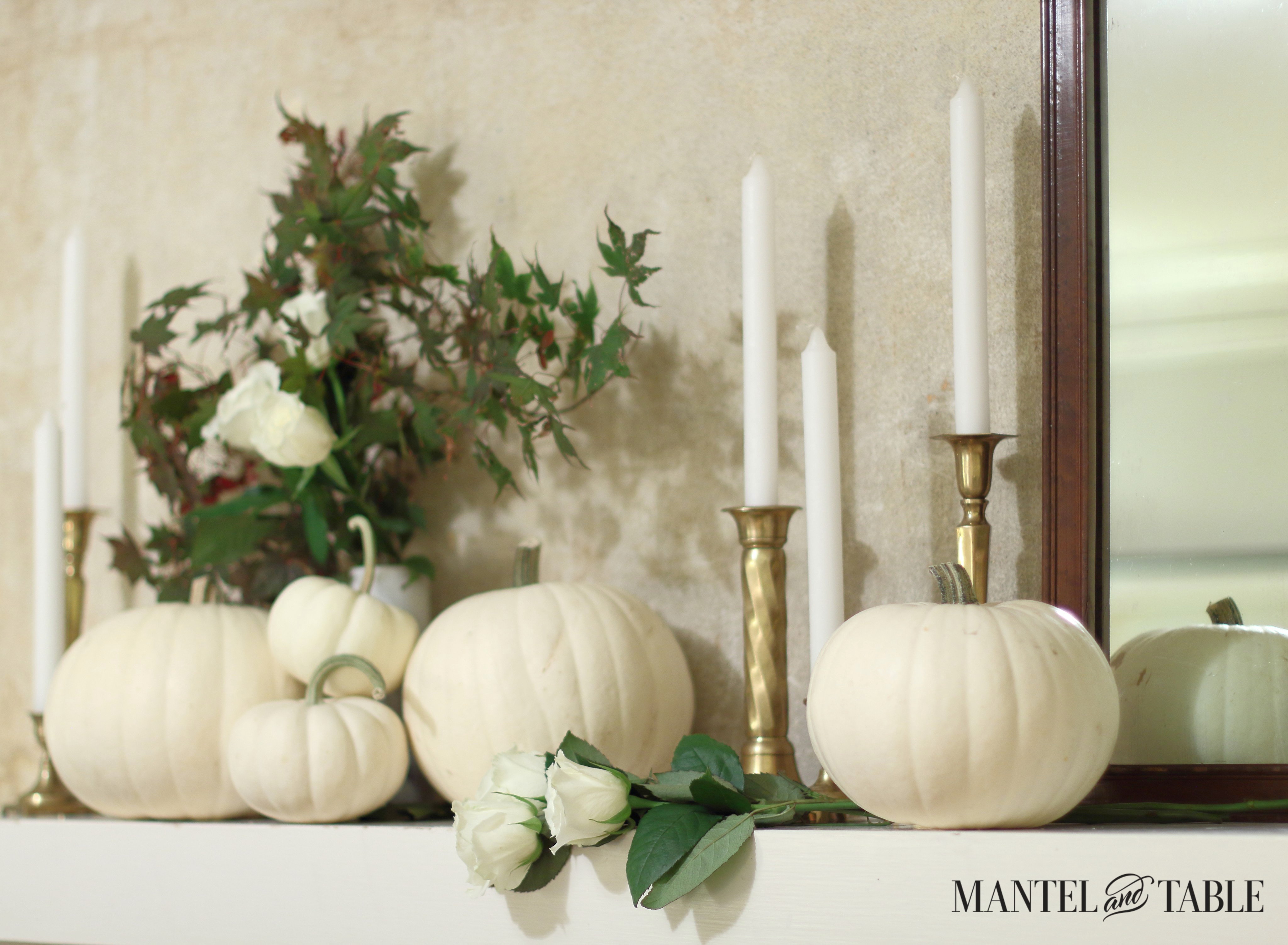 White pumpkins on white mantel, with brass candle holders, white candles,& white marble bud was with fall leaves & white roses.