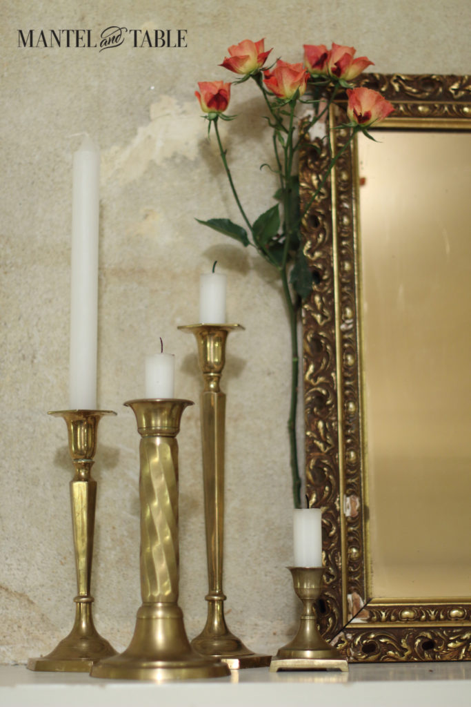 Peach roses, brass candlesticks, gold framed mirror on white mantel