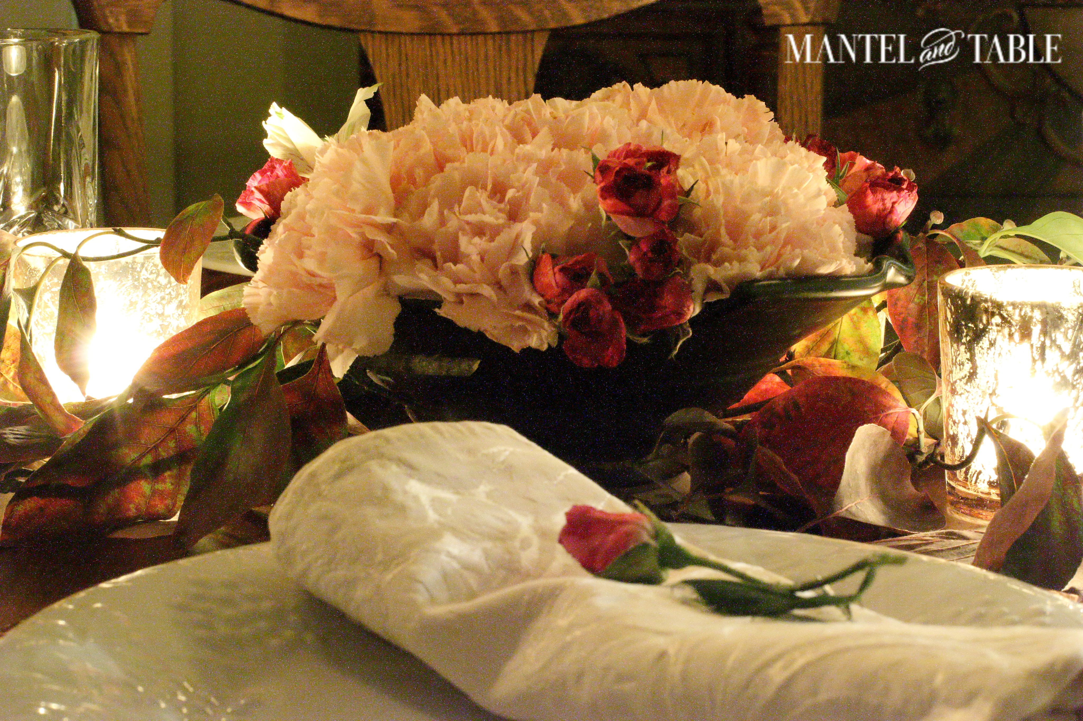 Blush napkin on white plates & copper charger with rose on top. Pink carnations, deep pink roses & fall leaves centerpiece, flickering votives.