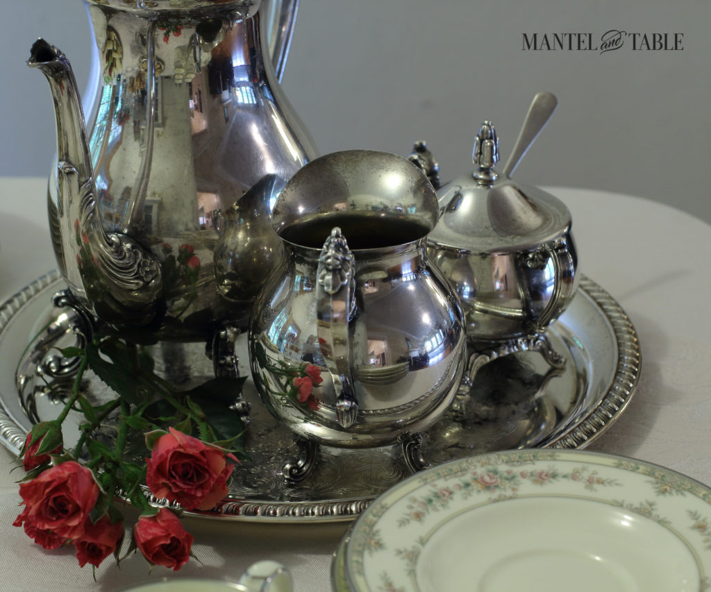 Silver tea service, stack of cream & pink flowered plates, deep pink roses, white tablecloth