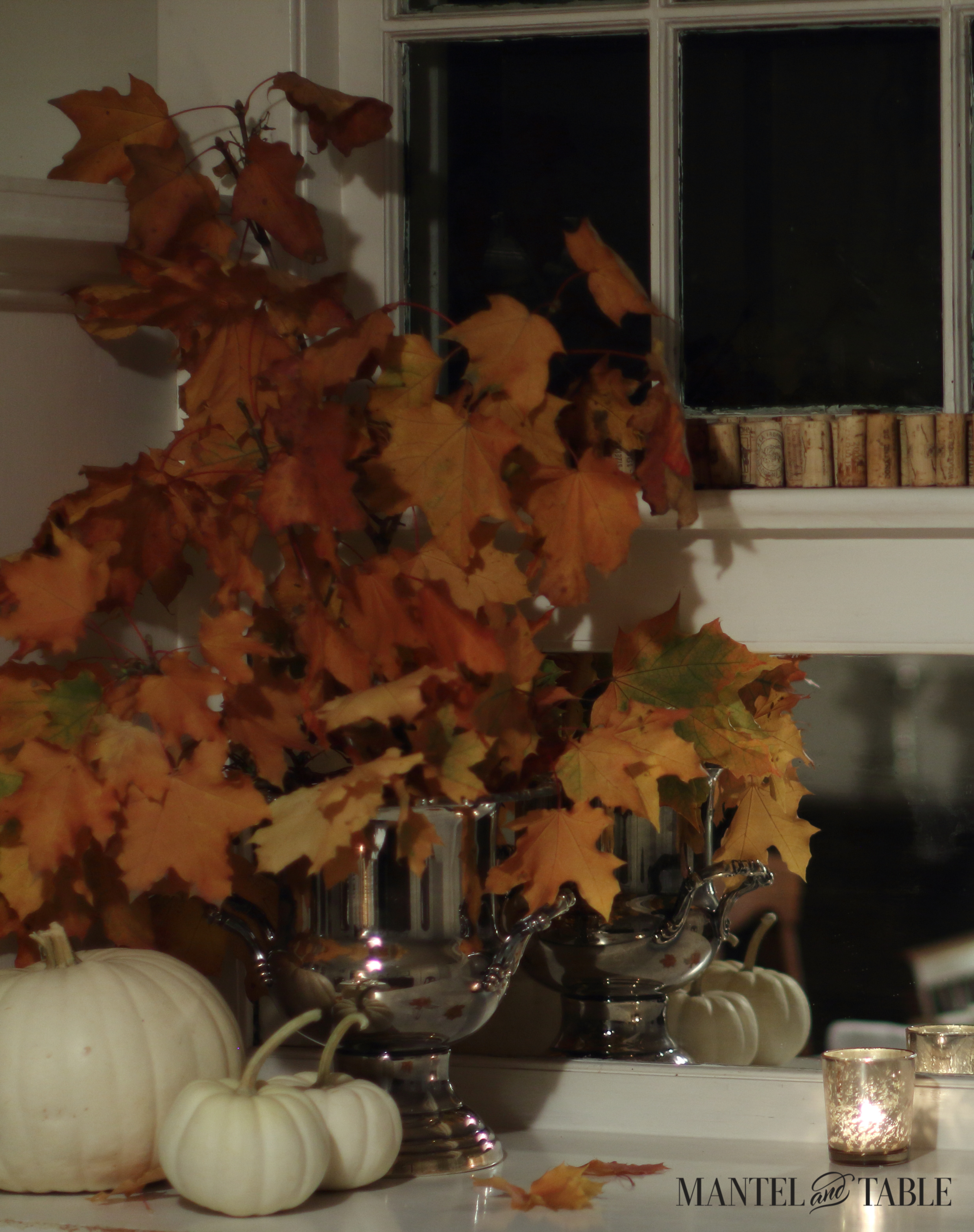 Fall leaves in silver wine bucket with white pumpkins and glowing gold votive