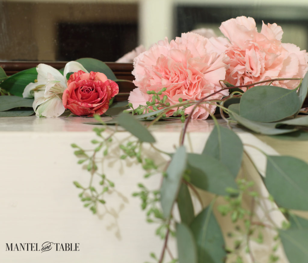 Deep pink roses, white alstroemeria, pink carnations, & seeded eucalyptus on the mantel