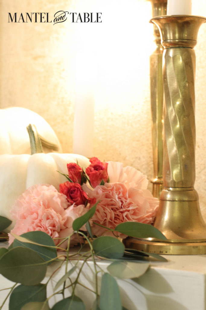 White pumpkins, pink flowers, brass candlesticks, candle glow