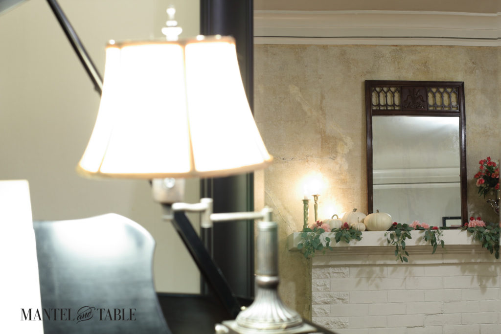 Mantel reflected in black framed full length mirror behind piano