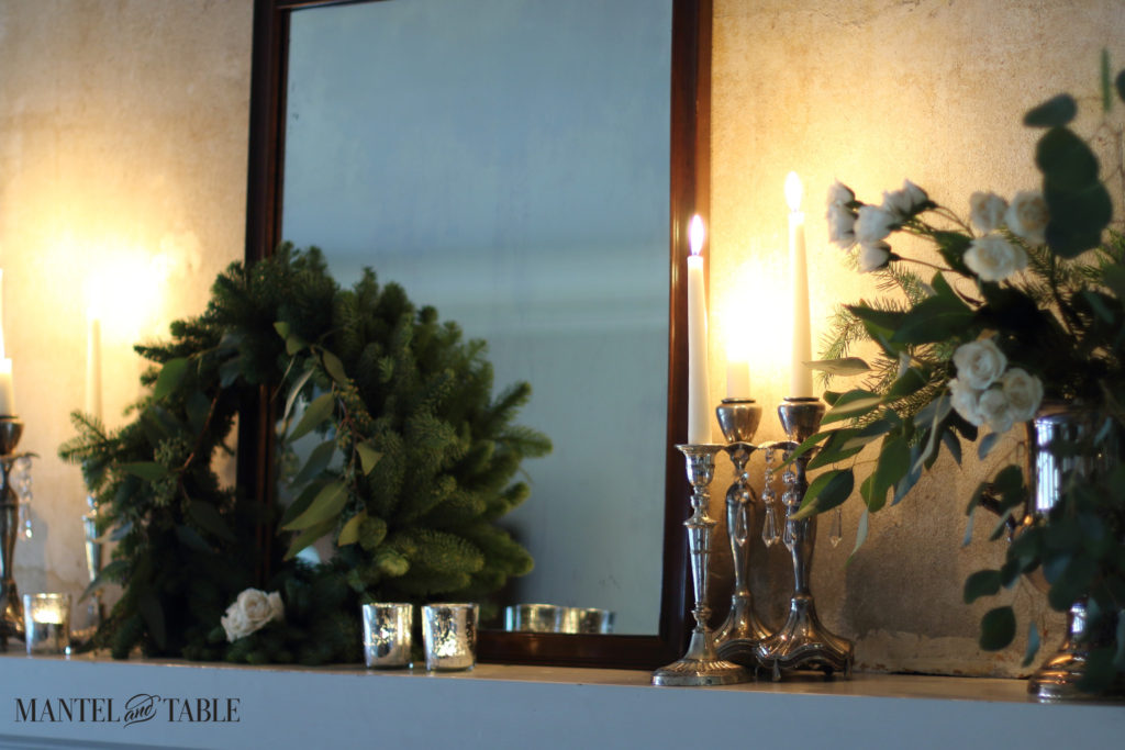 White mantel with evergreens & candlelight