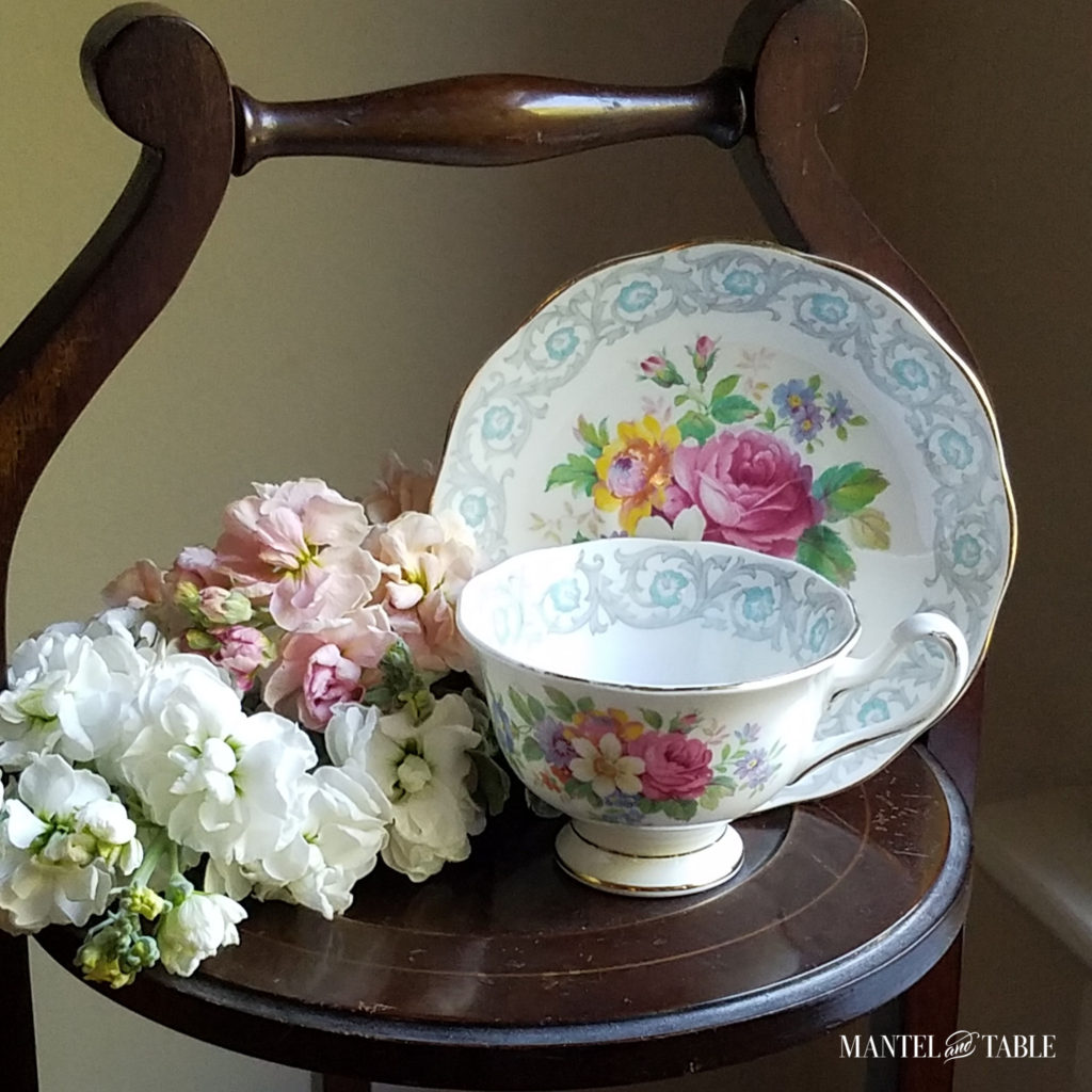 white blue, and pink flowered teacup on vintage wooden tiered stand, with pale pastel flowers