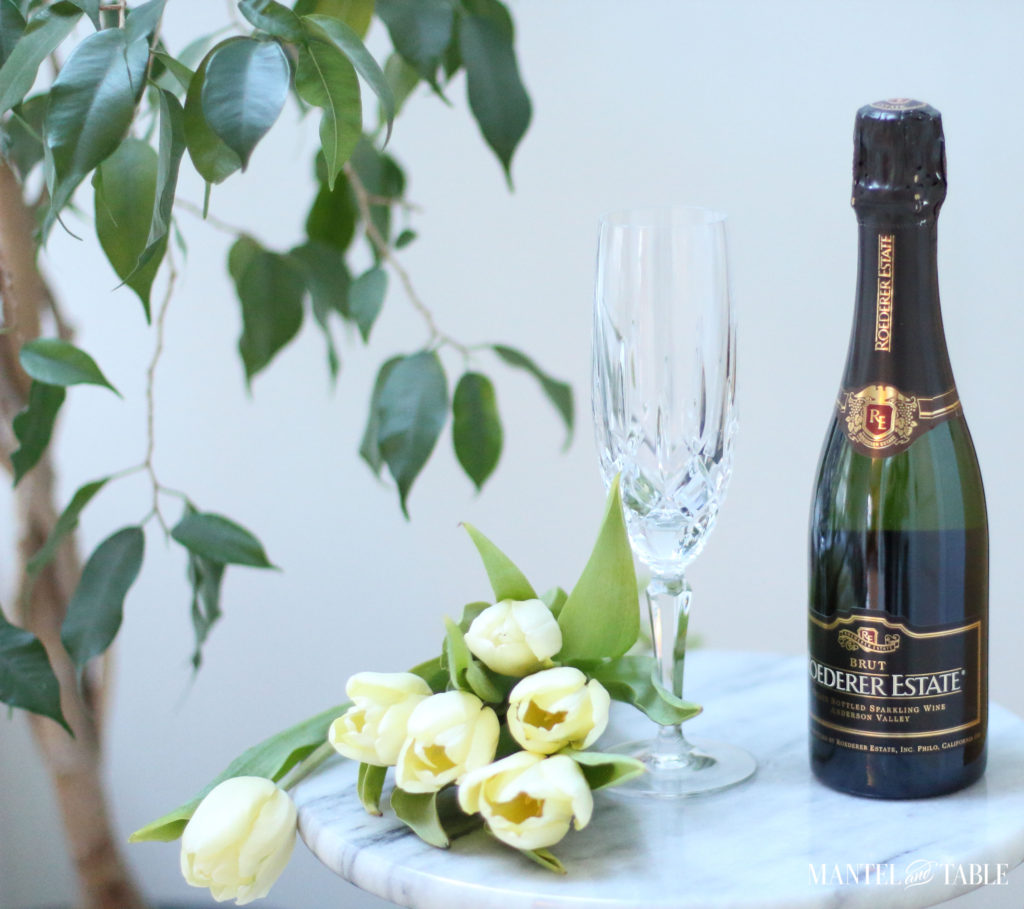 Spa Day ~ Bottle of sparkling wine and champagne flute on marble table, yellow tulips