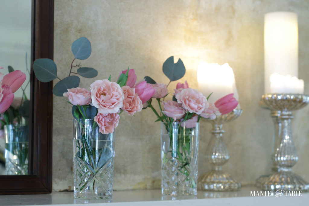 pink flowers in crystal vases on mantel with candlelight