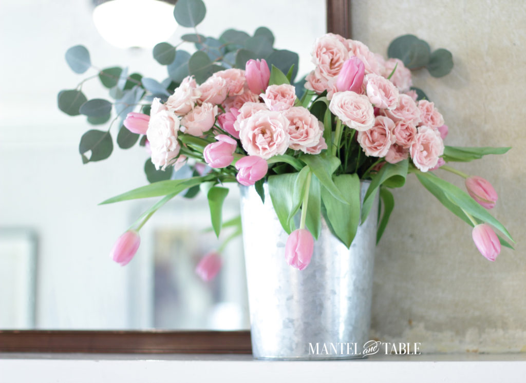pink roses & tulips with eucalyptus in galvanized metal bucket on mantel in front of mirror