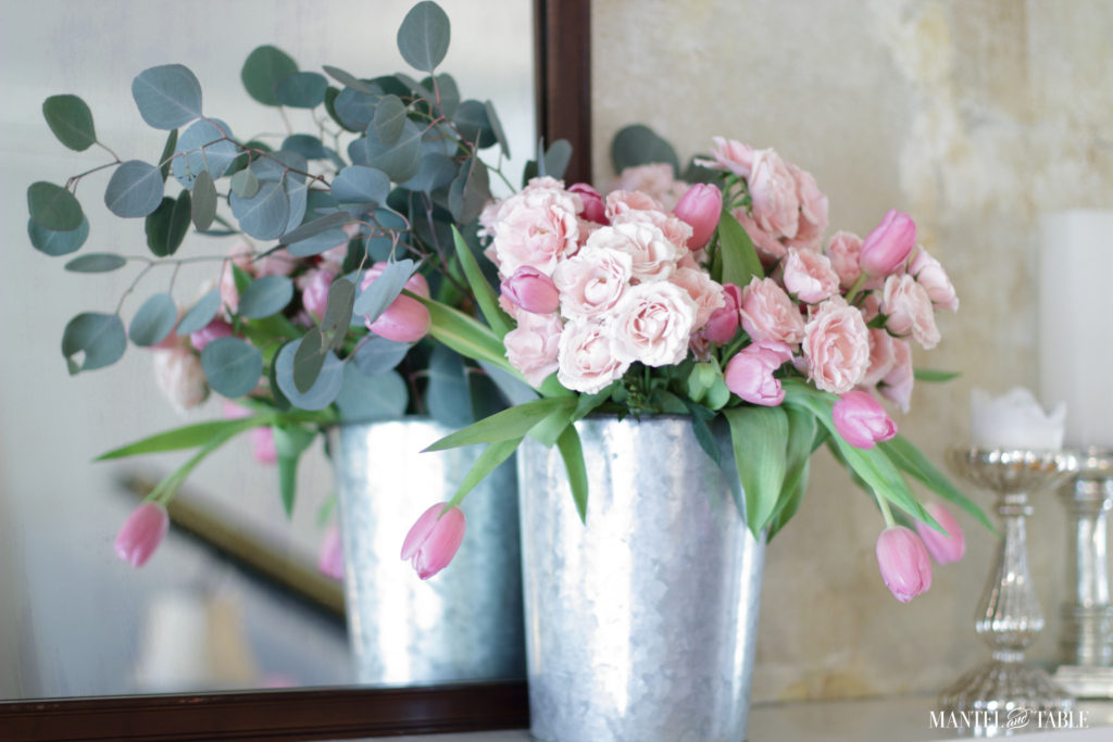 Pink roses & tulips, eucalyptus in silver metal bucket on mantel with silver pillar candle holders