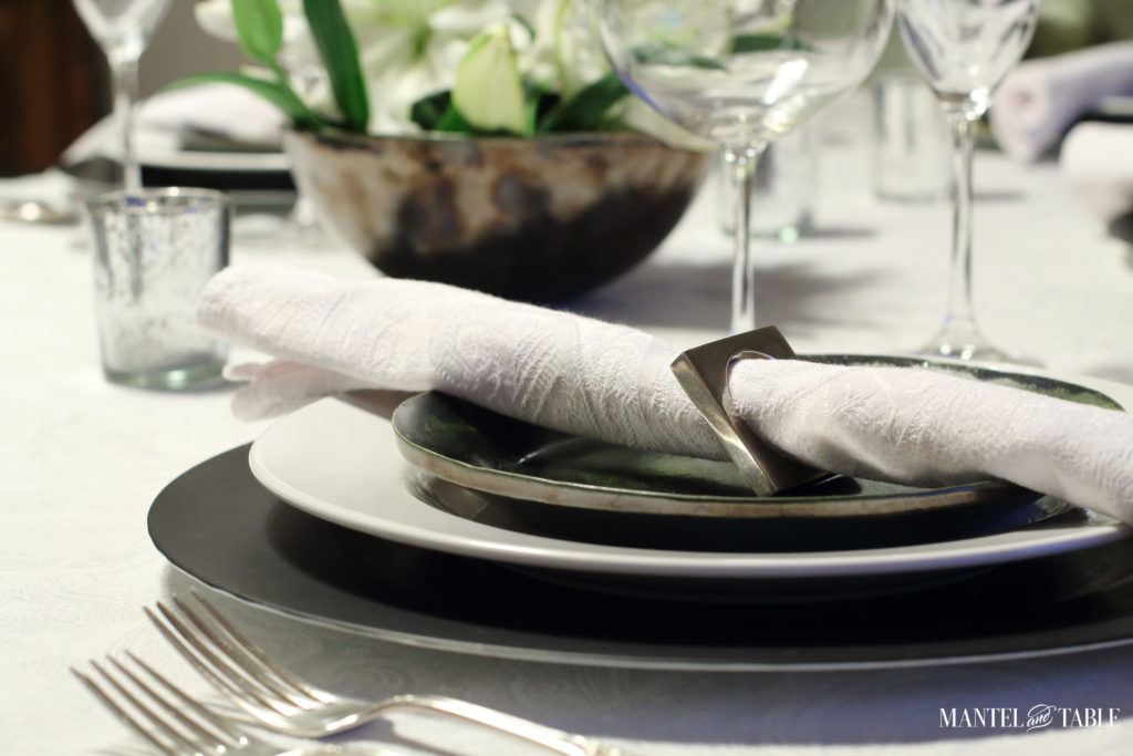 Black & white industrial table setting with centerpiece of white lilies - side of plate stack with napkin in ring
