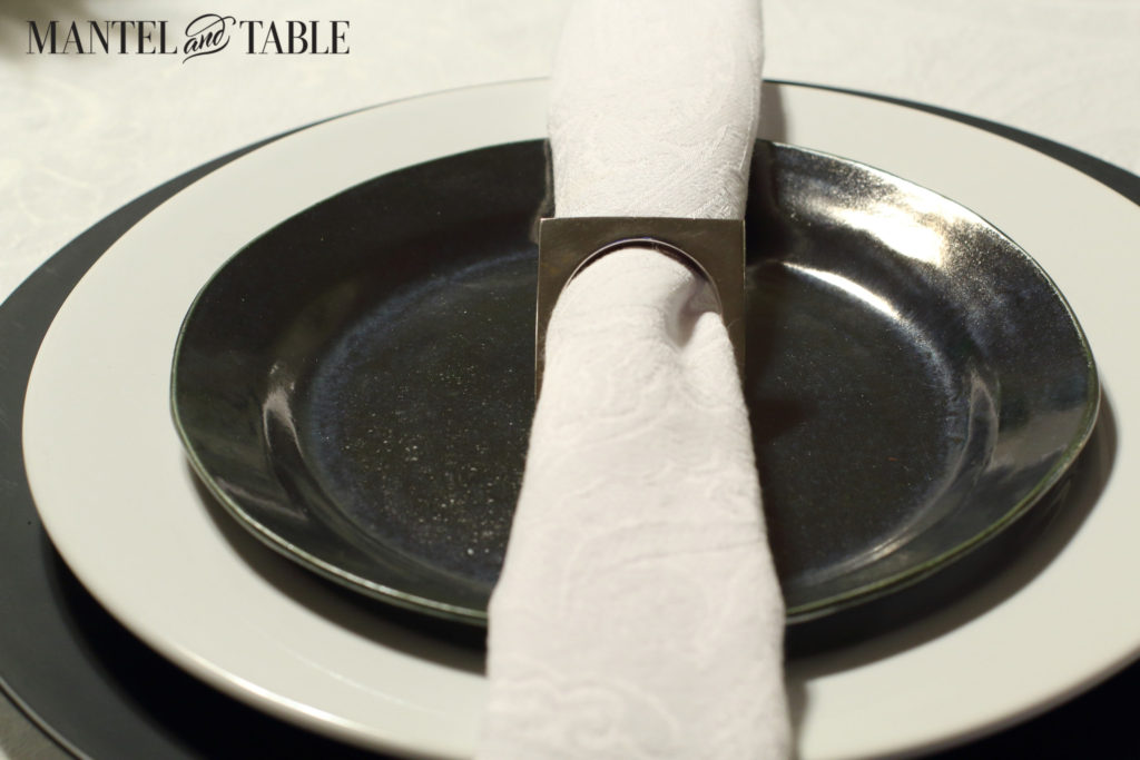 Black & white industrial table setting with centerpiece of white lilies-closeup of plate stack