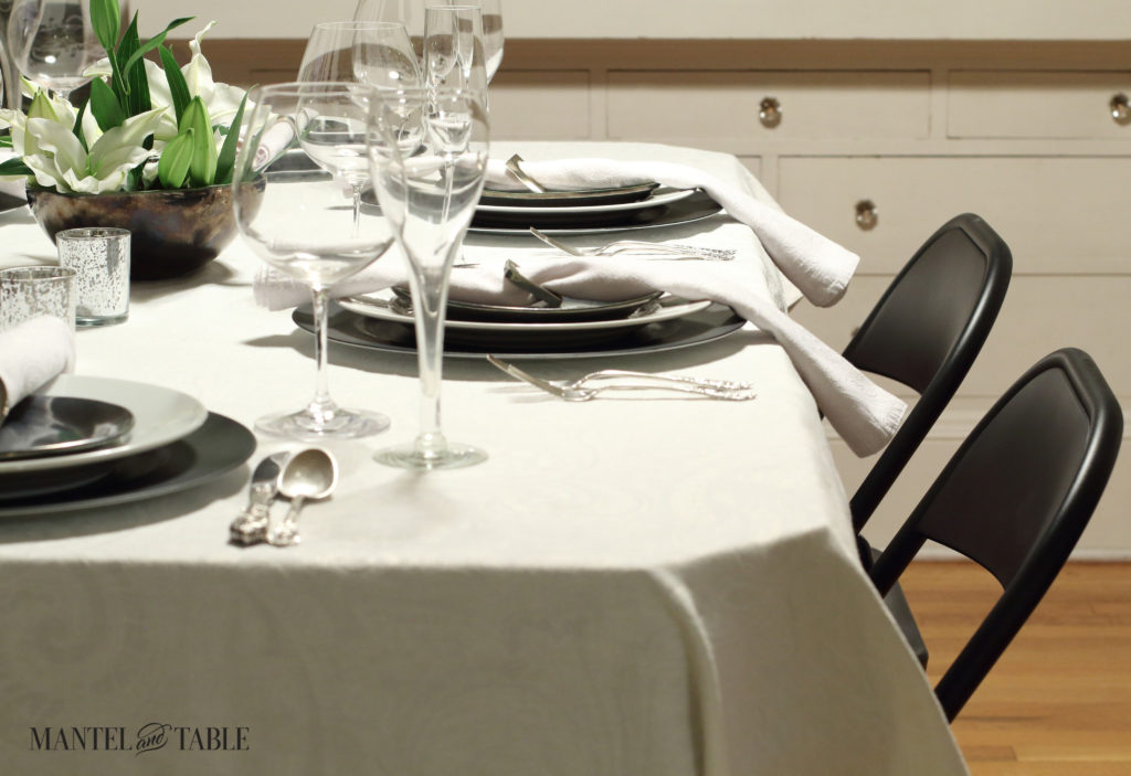 Black & white industrial table setting with centerpiece of white lilies-view of black metal chairs on one side