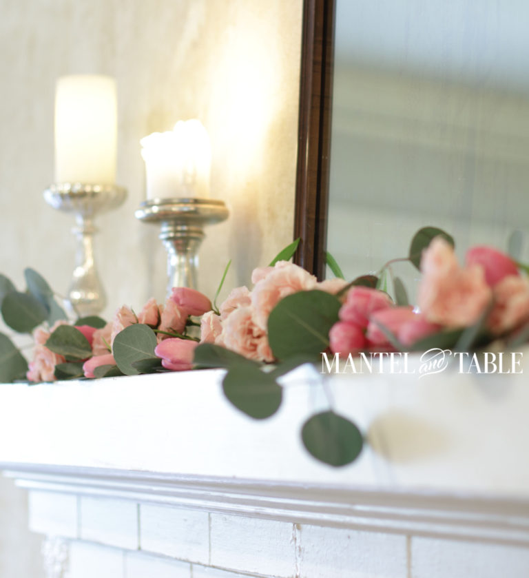 Closeup pink rose garland on mantel. candlelight & mirror