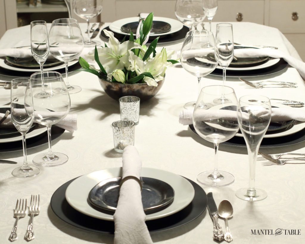 Black & white industrial table setting with centerpiece of white lilies- view from head of table