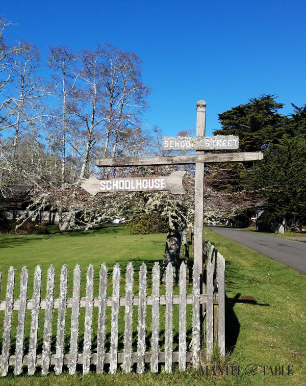 Old wooden sign inside a picket fence, pointing to the Oysterville schoolhouse