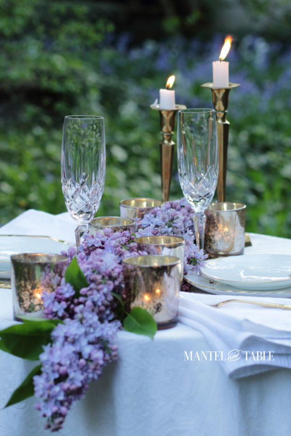 formal outdoor dinner table for two with candles, white tablecloth, lilacs.