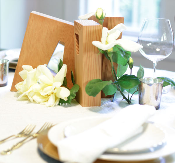 Gold & white place setting with work of art wood blocks centerpiece. Yellow roses.
