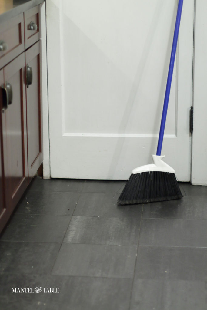 Broom leaning against the door with dirty floor