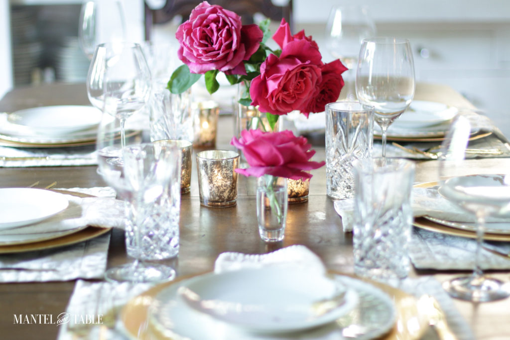 Deep pink roses on blush and gold table setting. Lots of crystal glasses.