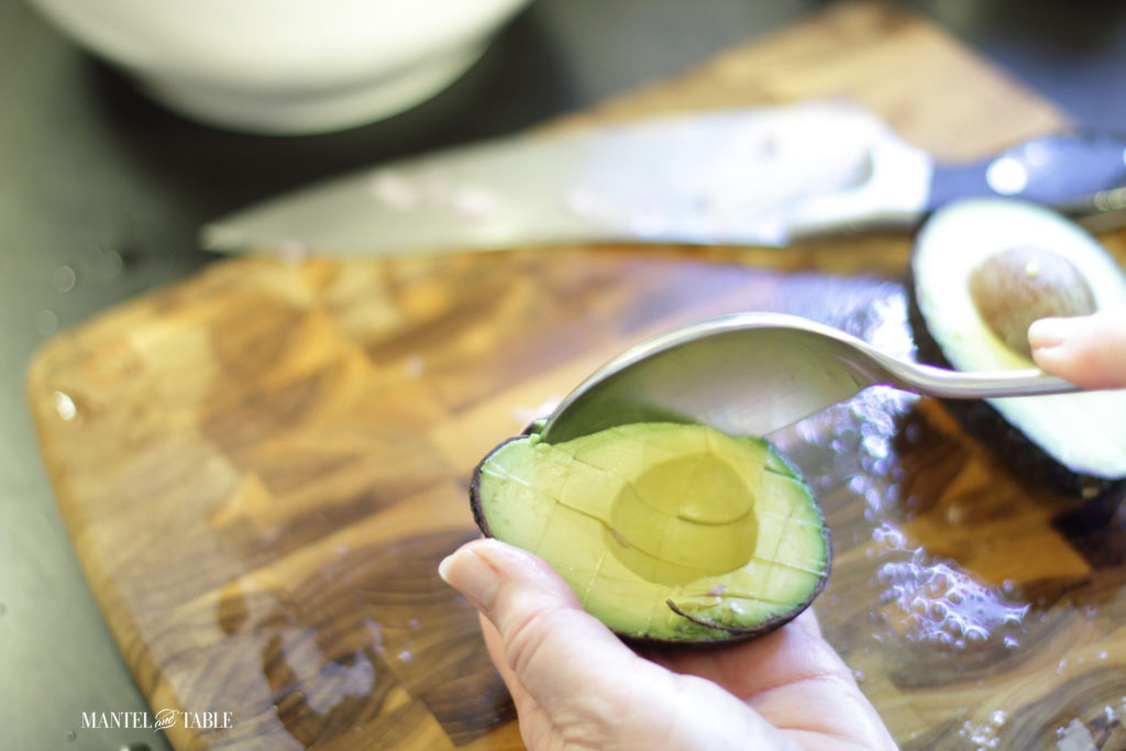 Scooping the avocado squares out with a spoon for grapefruit avocado salad
