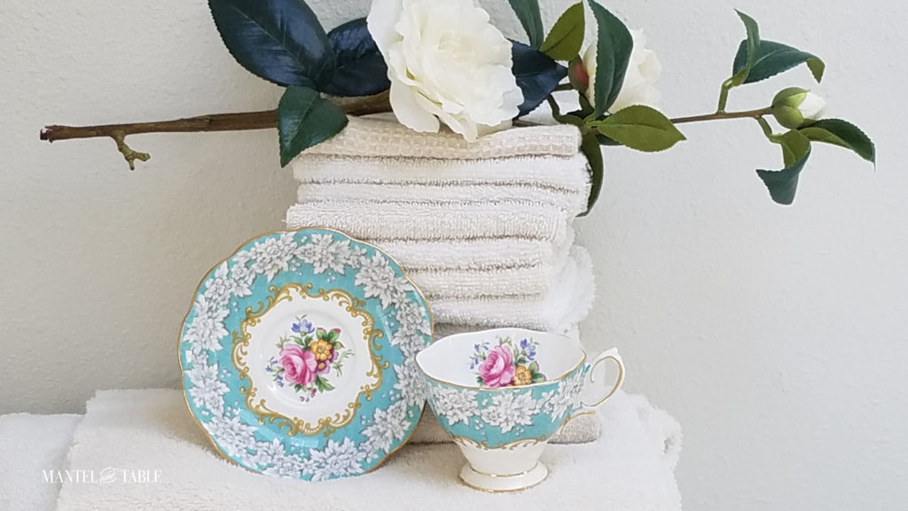 Royal Albert Enchantment Teacup and saucer with a stack of fluffy white towels, white camellia branch