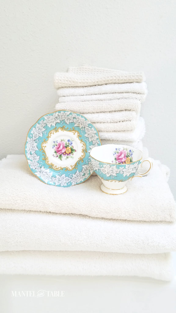 Enchantment Teacup and saucer with a stack of fluffy white towels