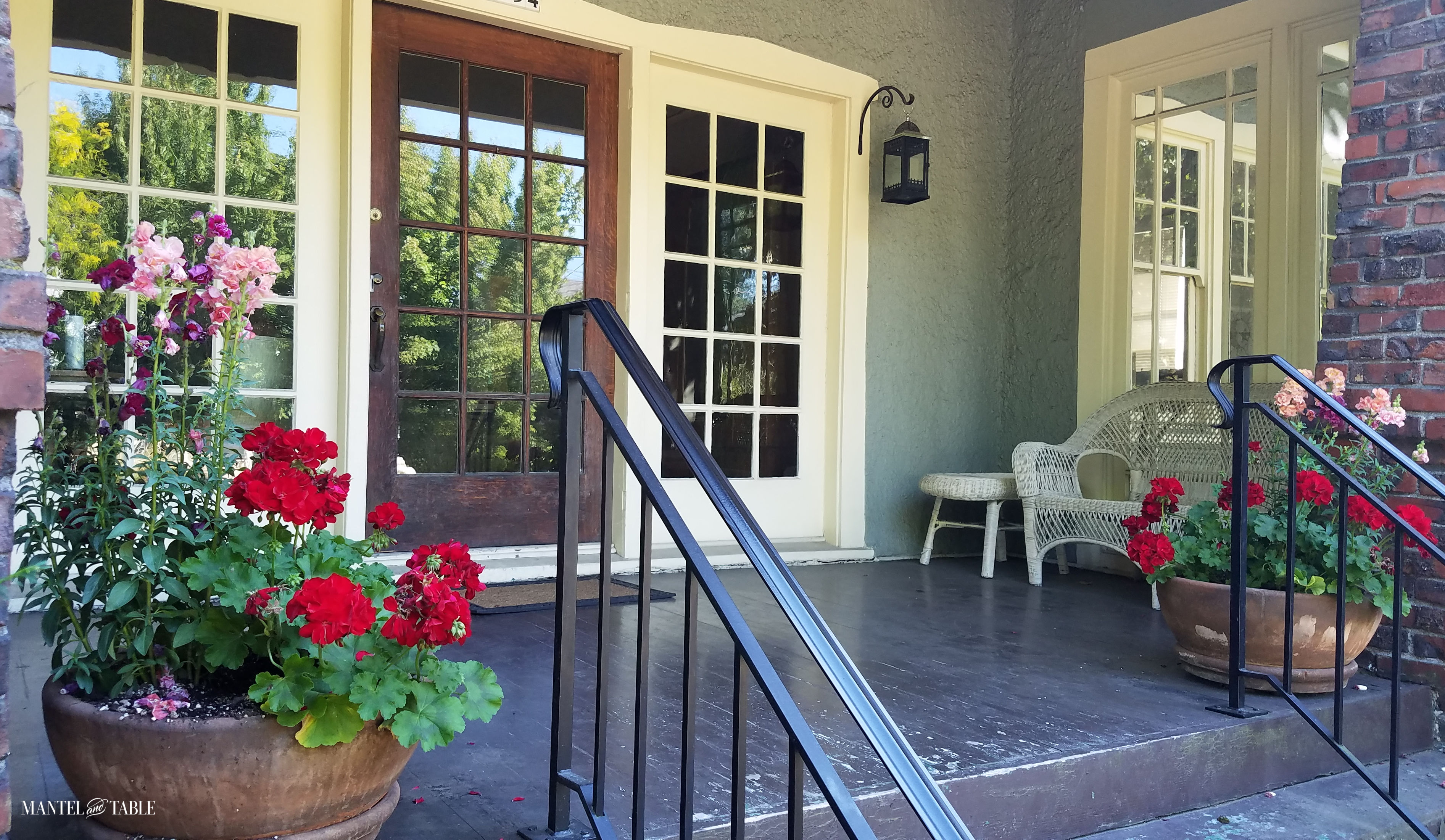 Front porch with beautiful red, pink, and salmon flowers in planters