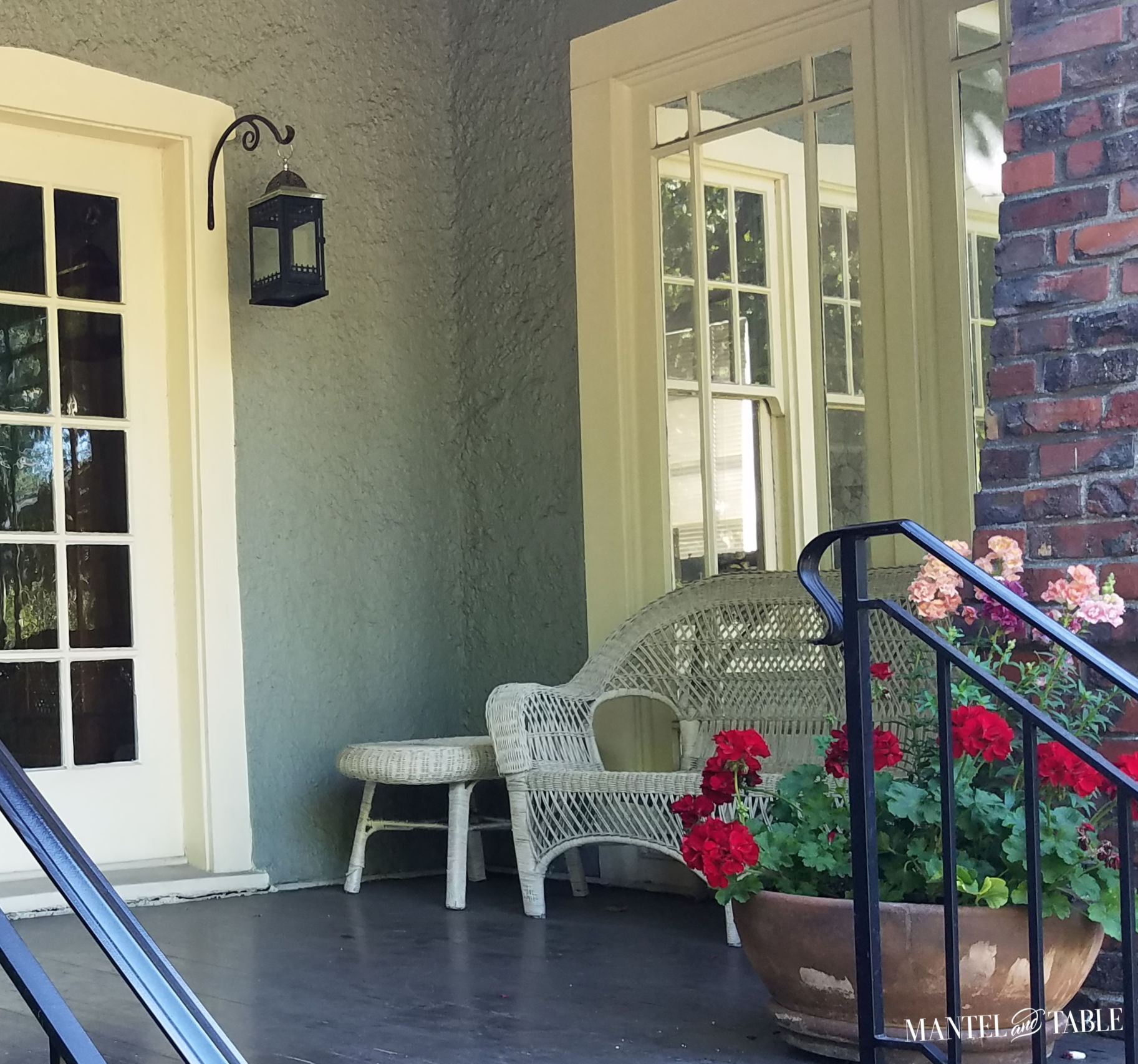 Front porch with wicker loveseat & table, flower planter with red and salmon flowers