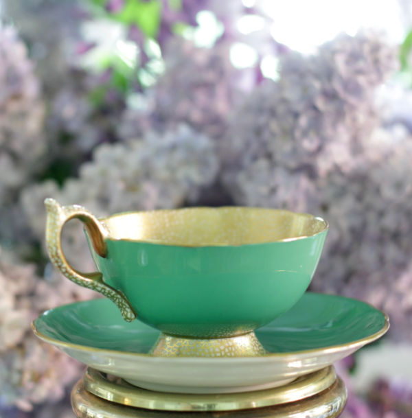 Closeup of Aynsely green & gold teacup with lilac and wisteria background