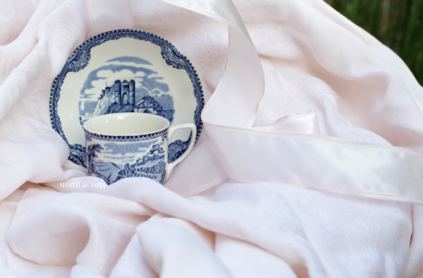 cup resting in front of saucer on patio chair draped in pink