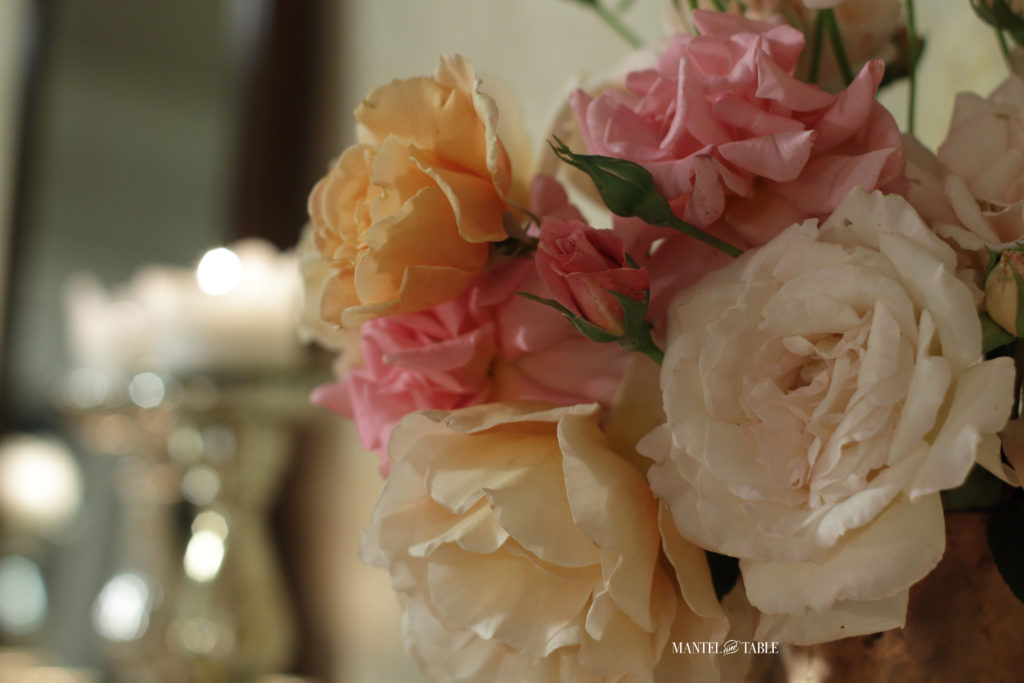Closeup of pink, cream & peach roses, candles in the background