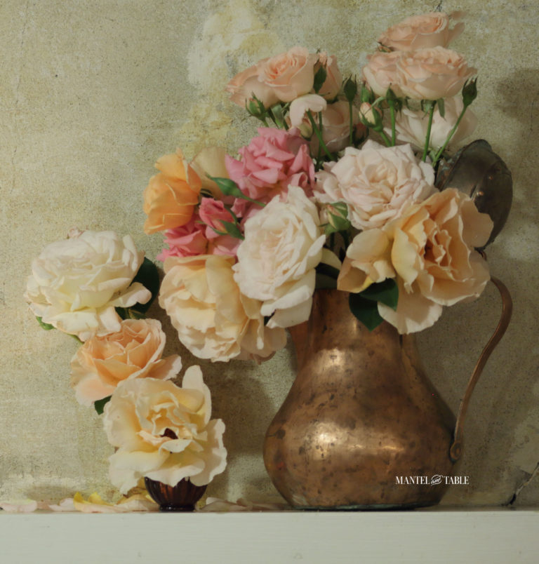 Closeup of copper vase of garden roses on the mantel
