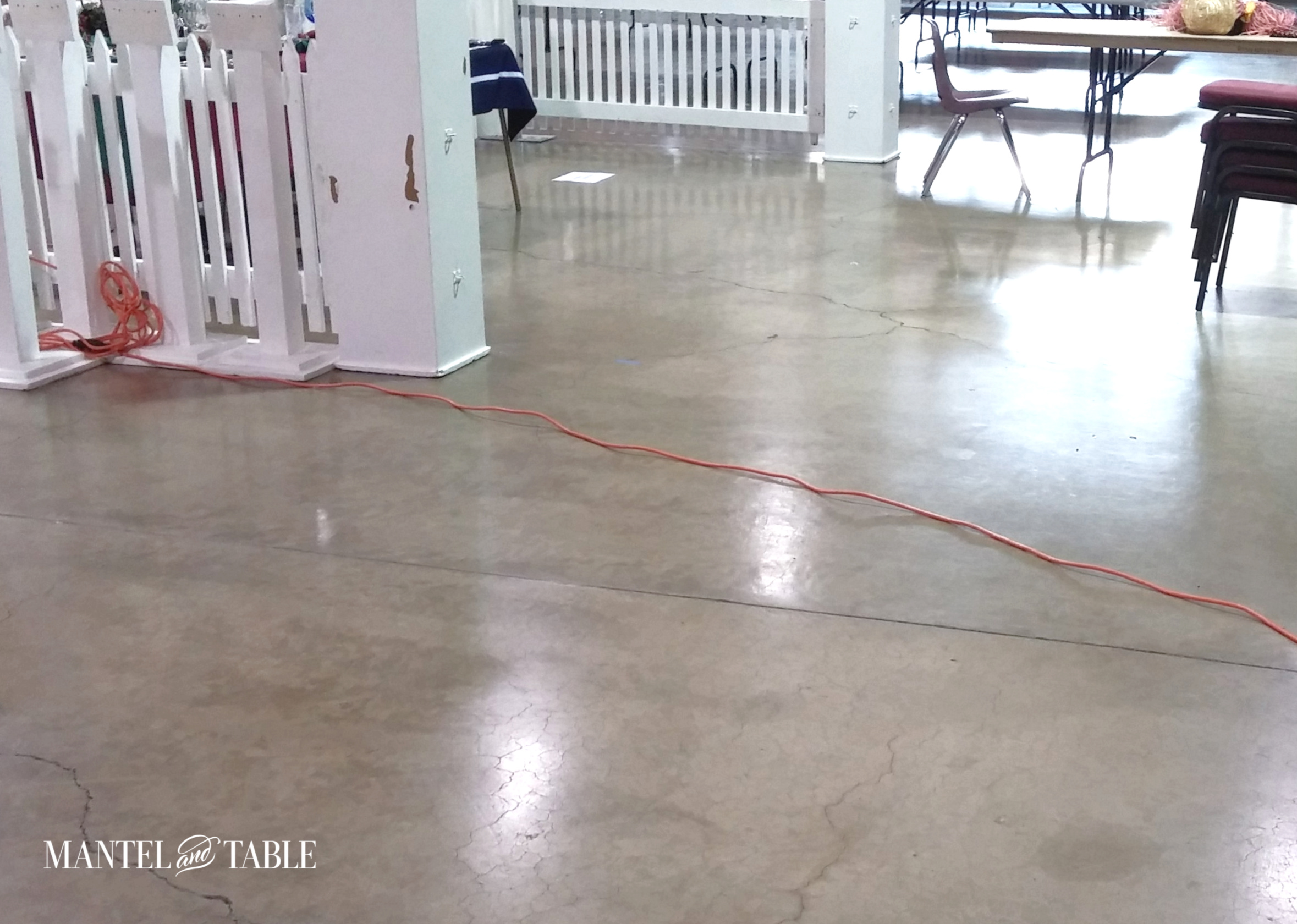 Bright orange extension cord going through some white fence panels and snaking across the exhibit hall floor