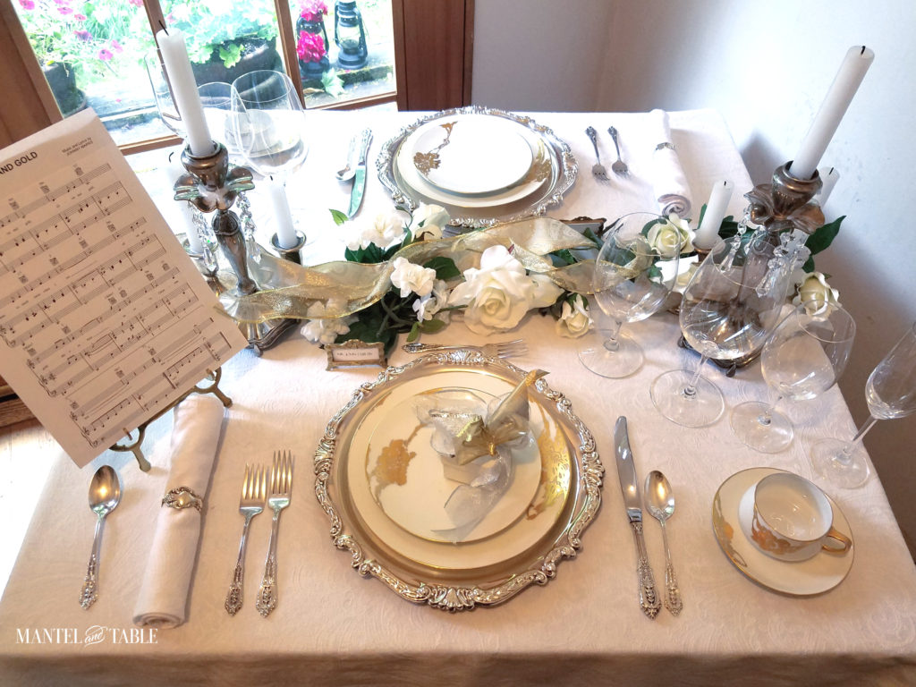 white silver & gold table setting with white rose & evergreen garland