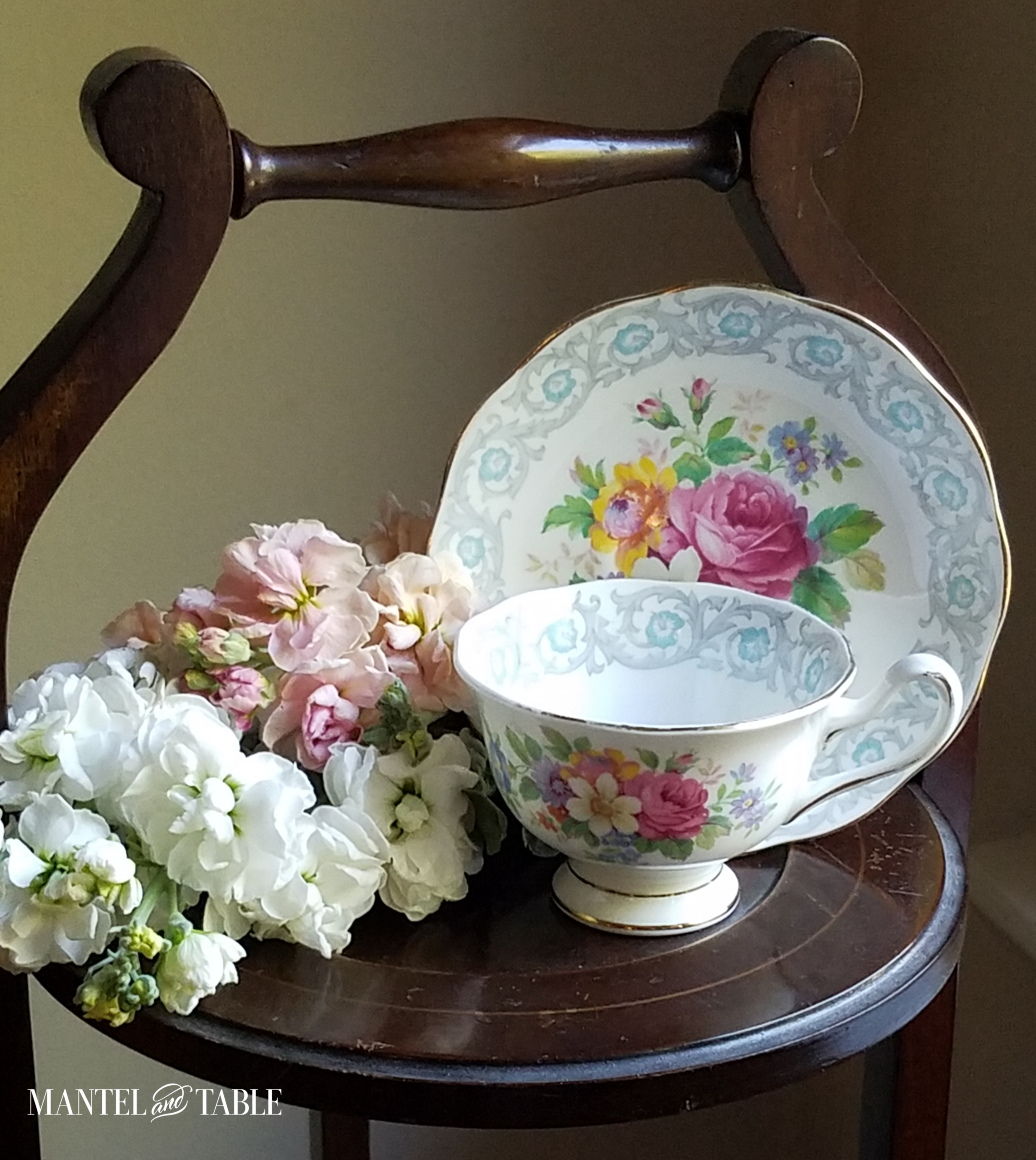Blue and grey trimmed cup and saucer with pink and yellow flowers in the middle