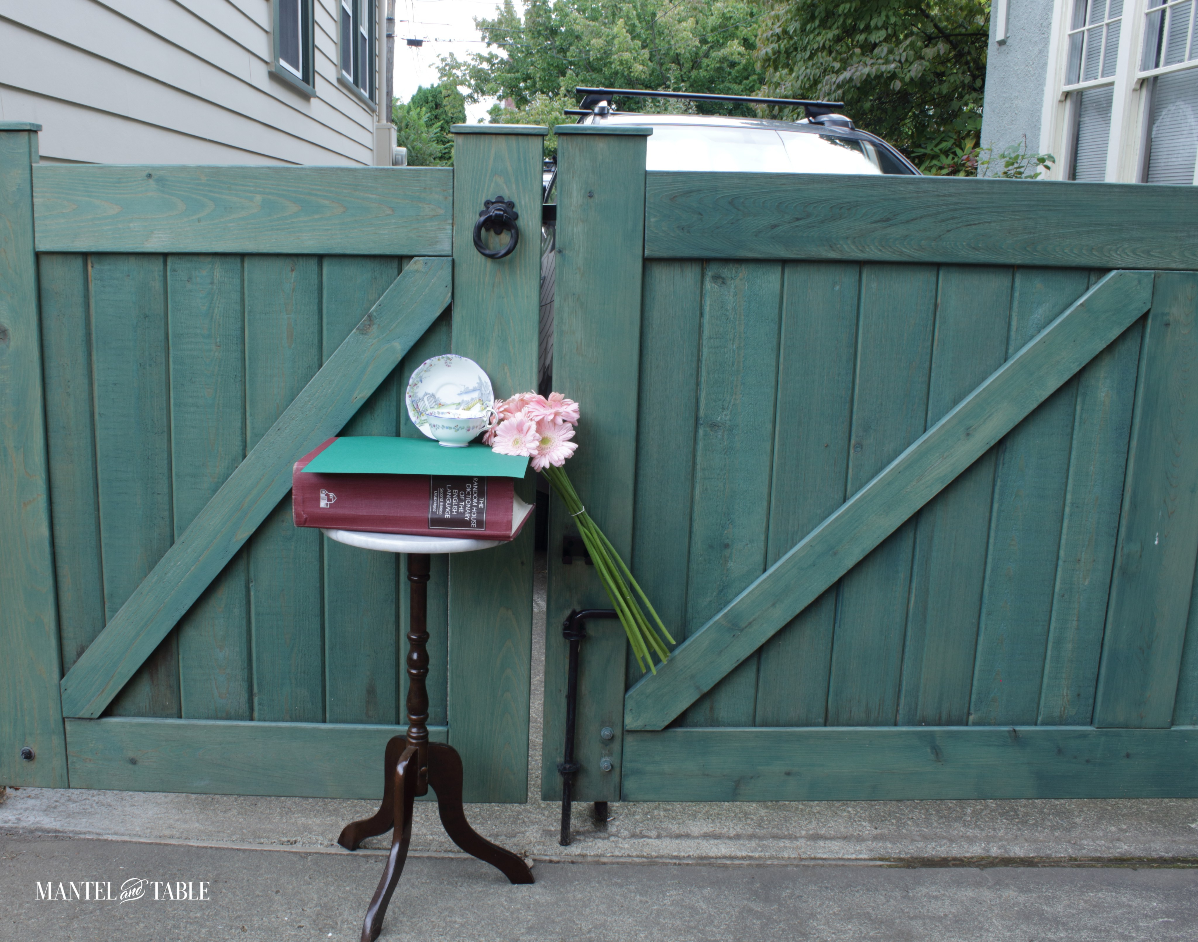 Rosedale teacup on a table in front of a green double gate in the driveway.