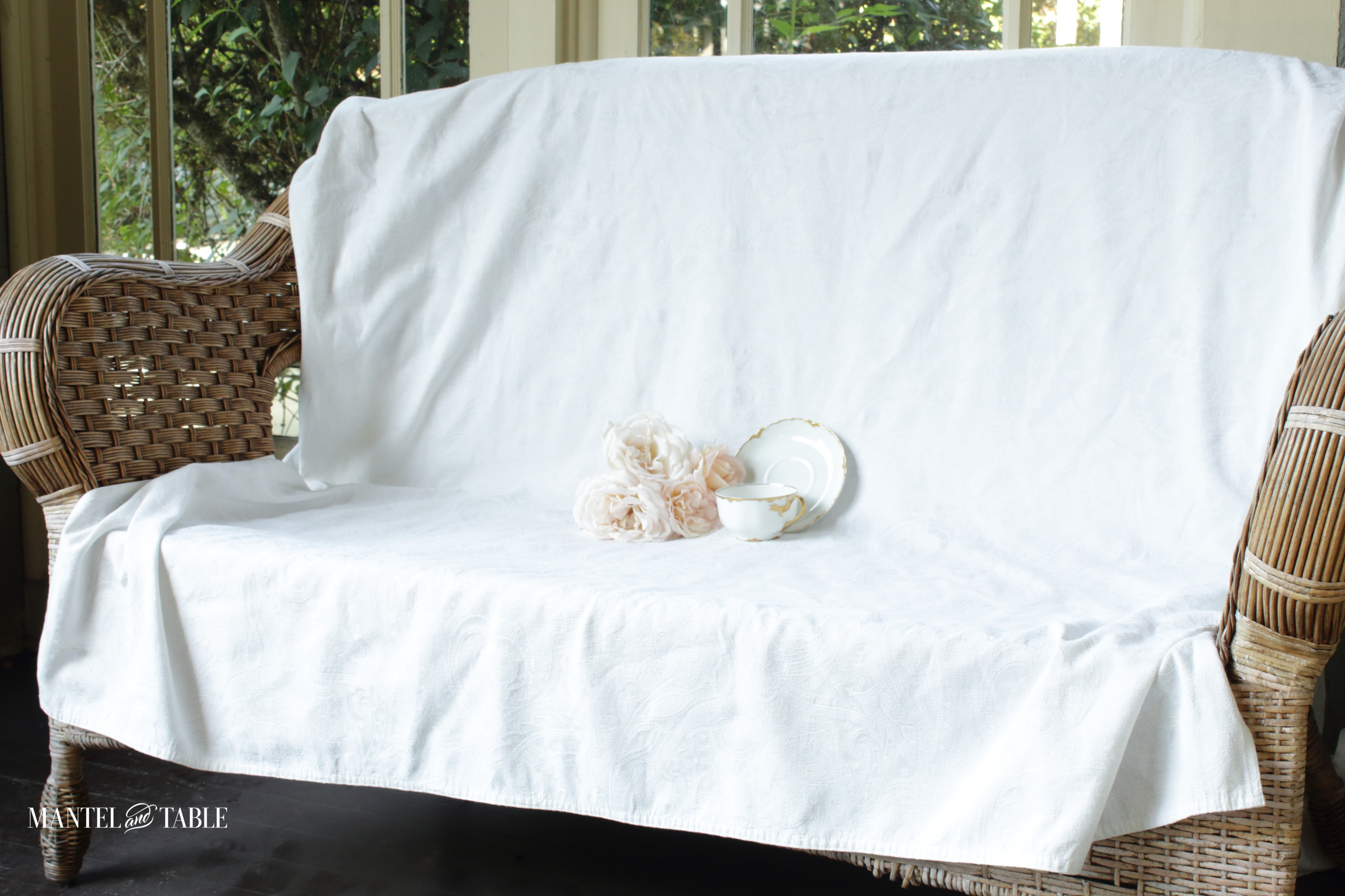 Wide view of love seat on front porch with roses and teacup