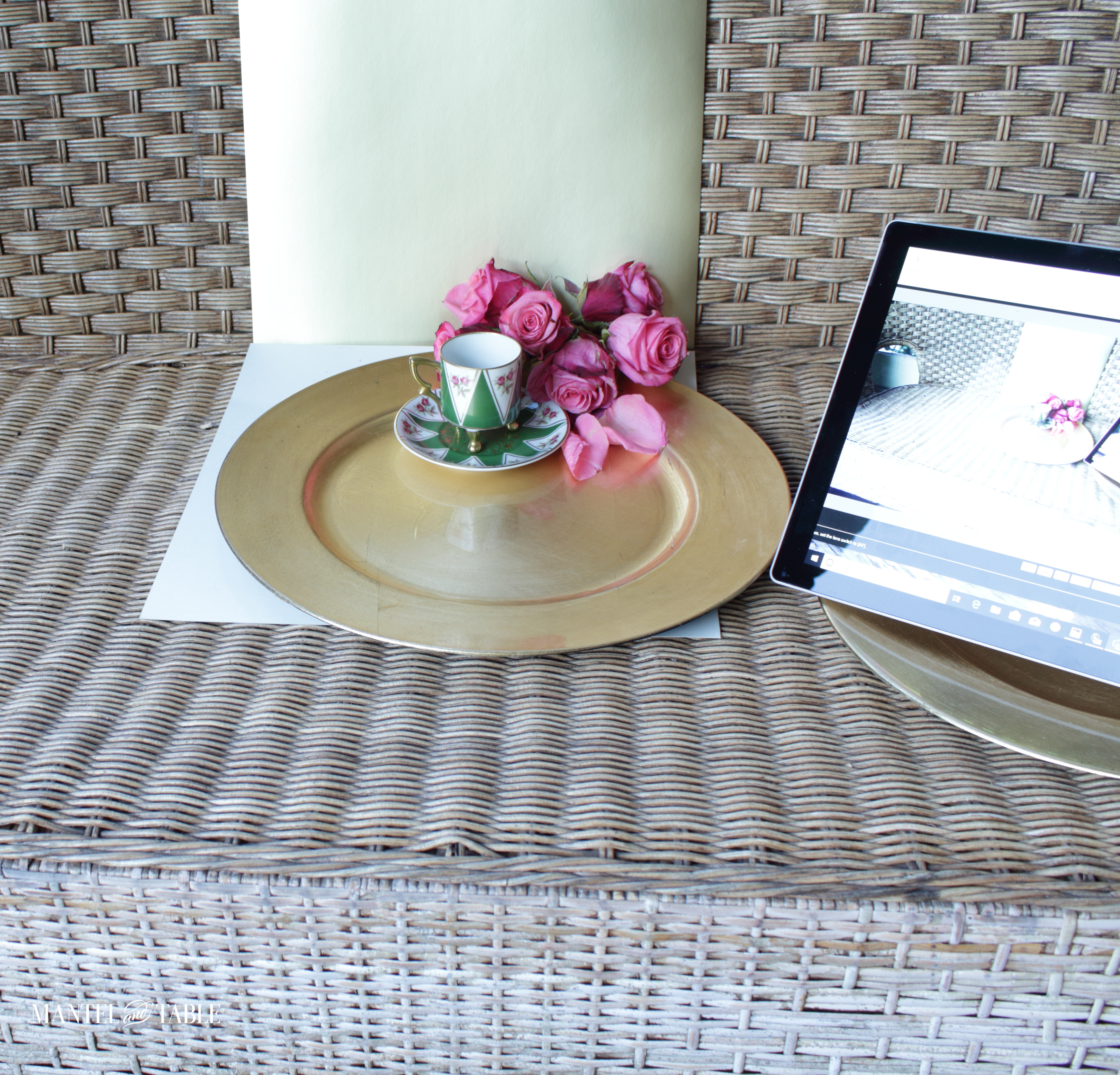 Demitasse teacup and saucer on background tagboard pieces on wicker love seat next to laptop