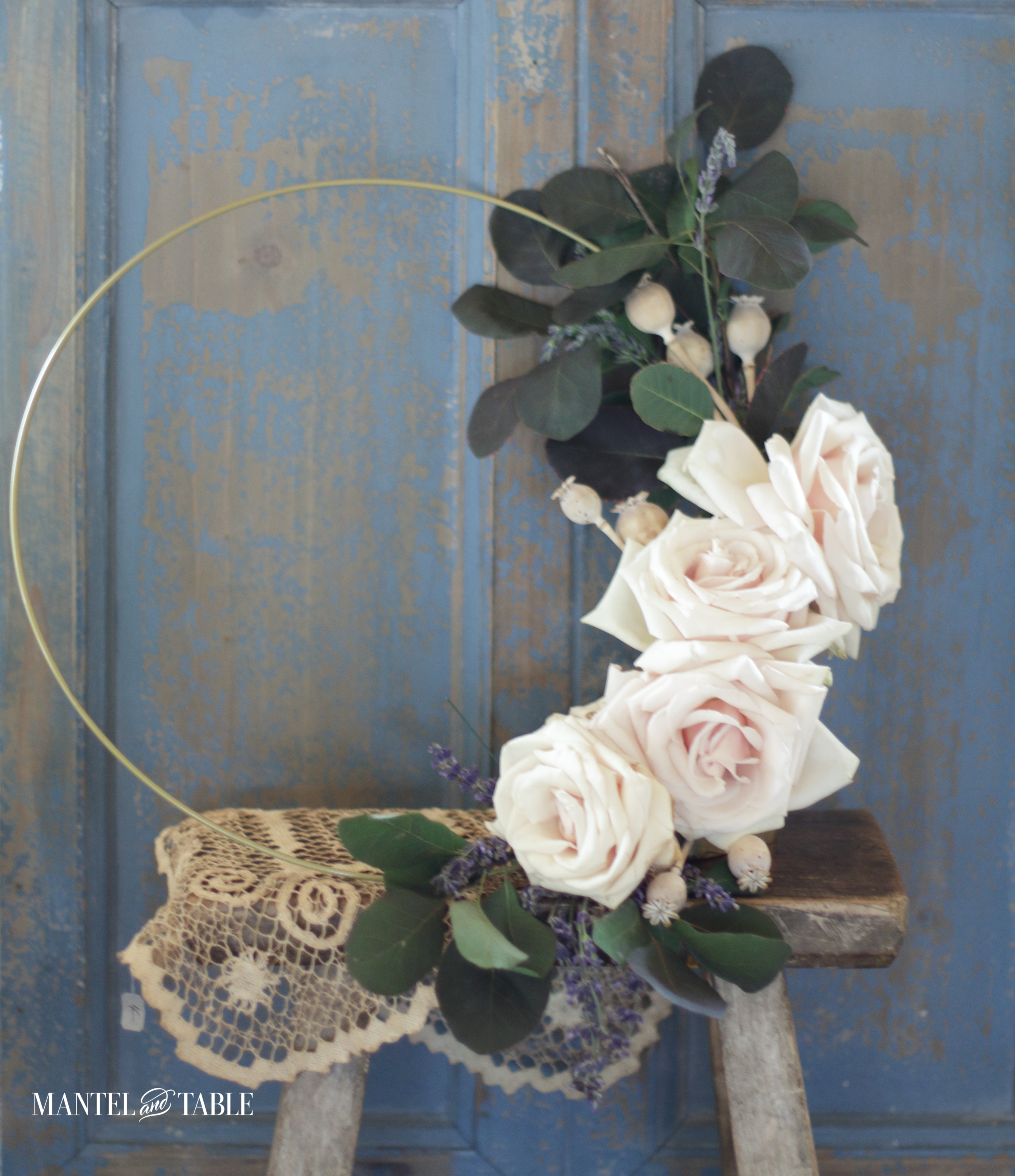 White roses and greenery on a gold hoop wreath
