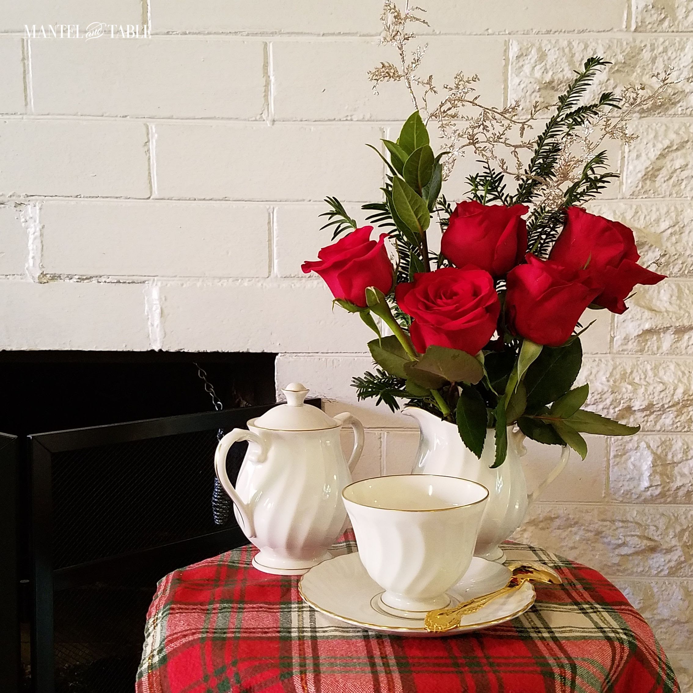 White teacup, creamer with gold rim. Red roses & evergreen arrangement. Mantel and Table