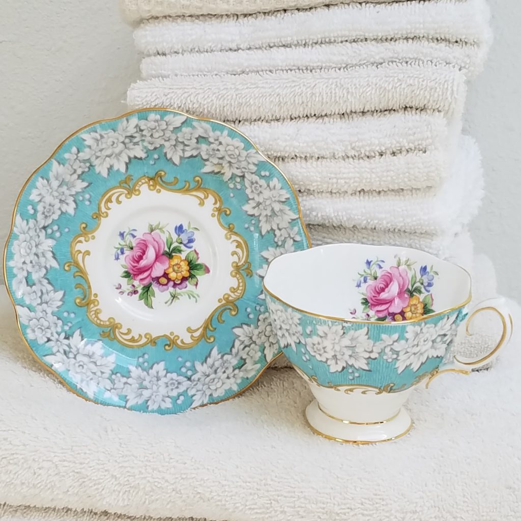 Turquoise flowered teacup with stack of white towels - Mantel and Table