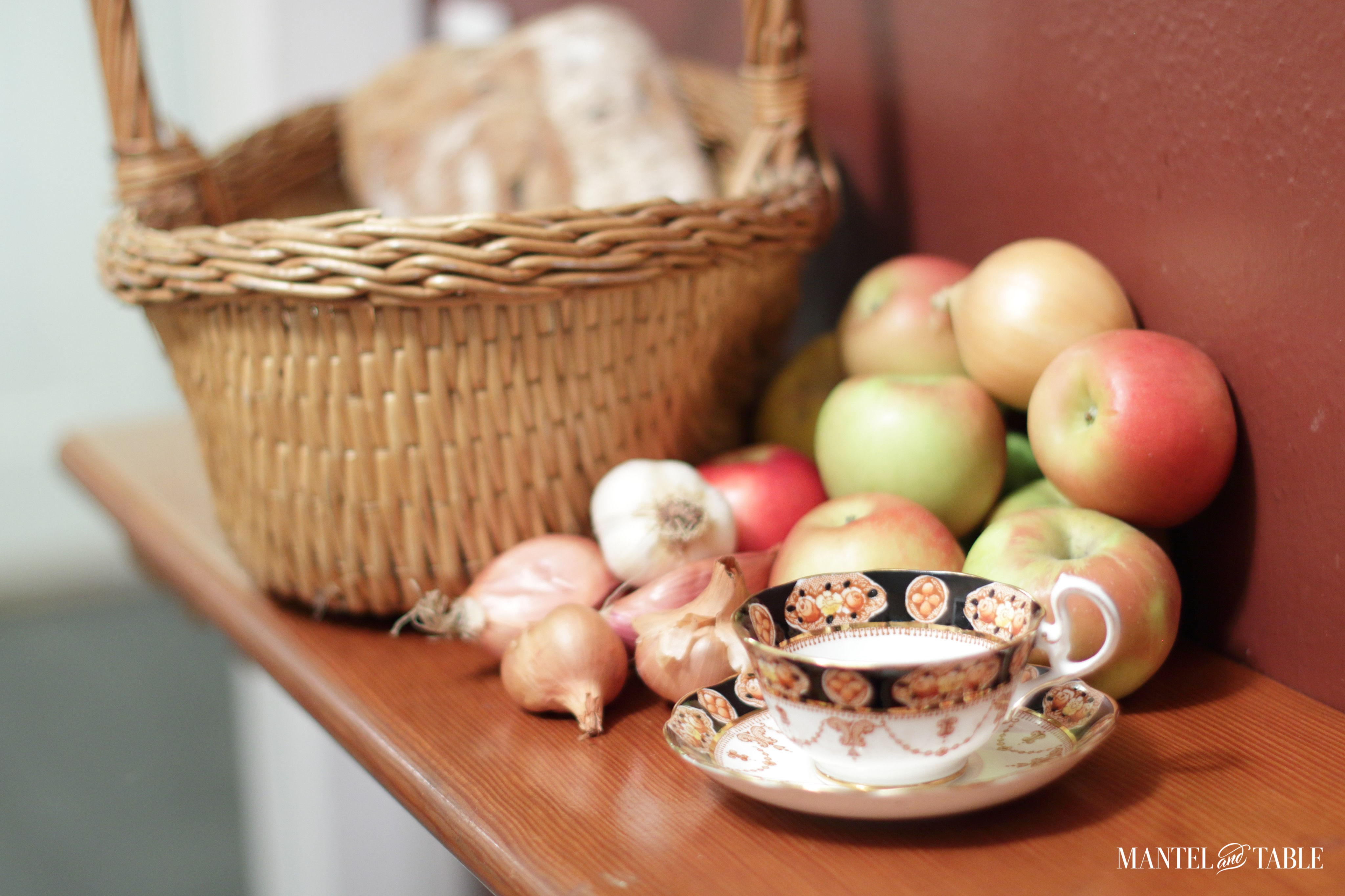 Teacup and apples on the counter with wicker basket
