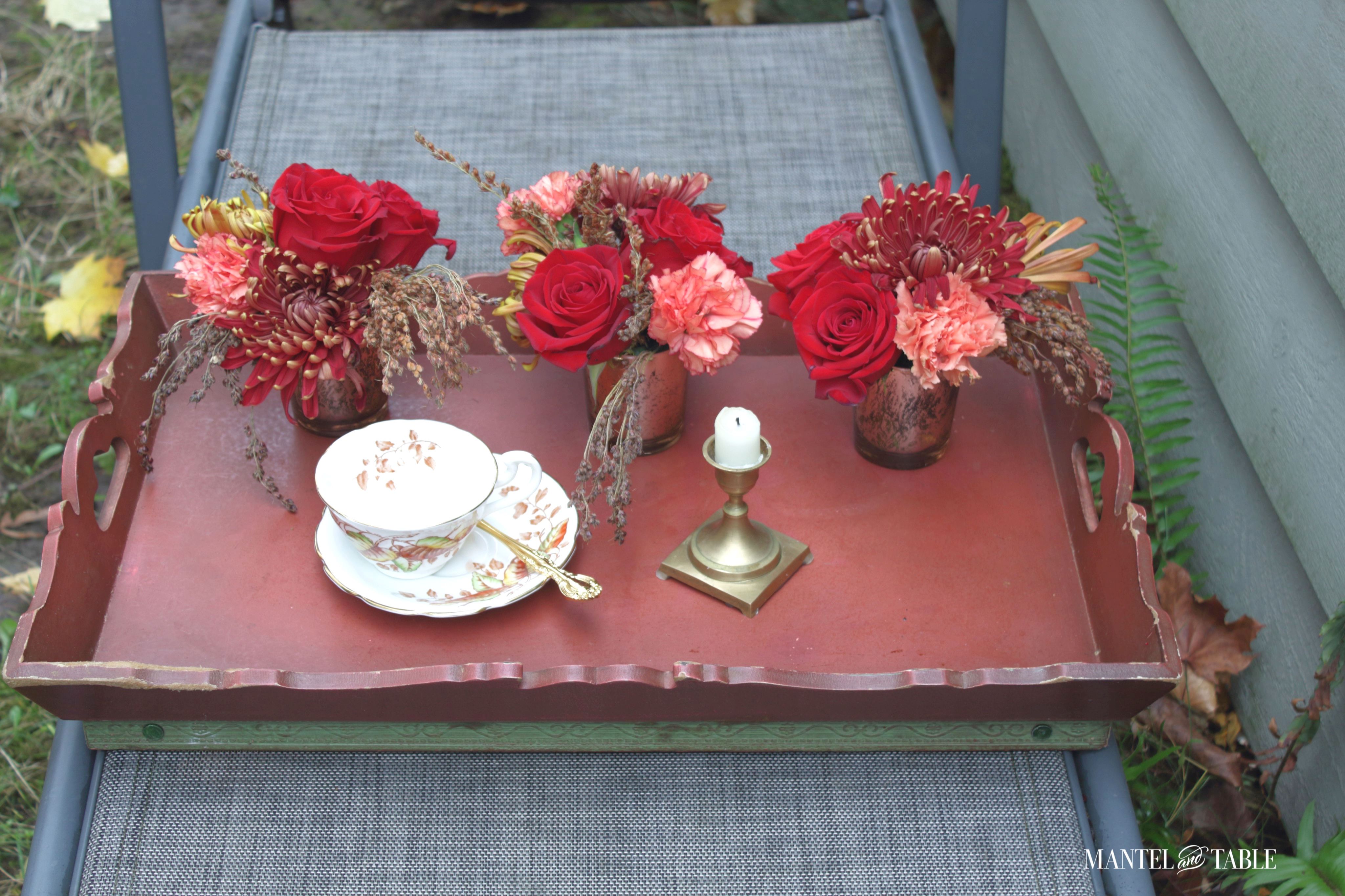 Teacup, flower arrangements, candleholder, sppon on a tray
