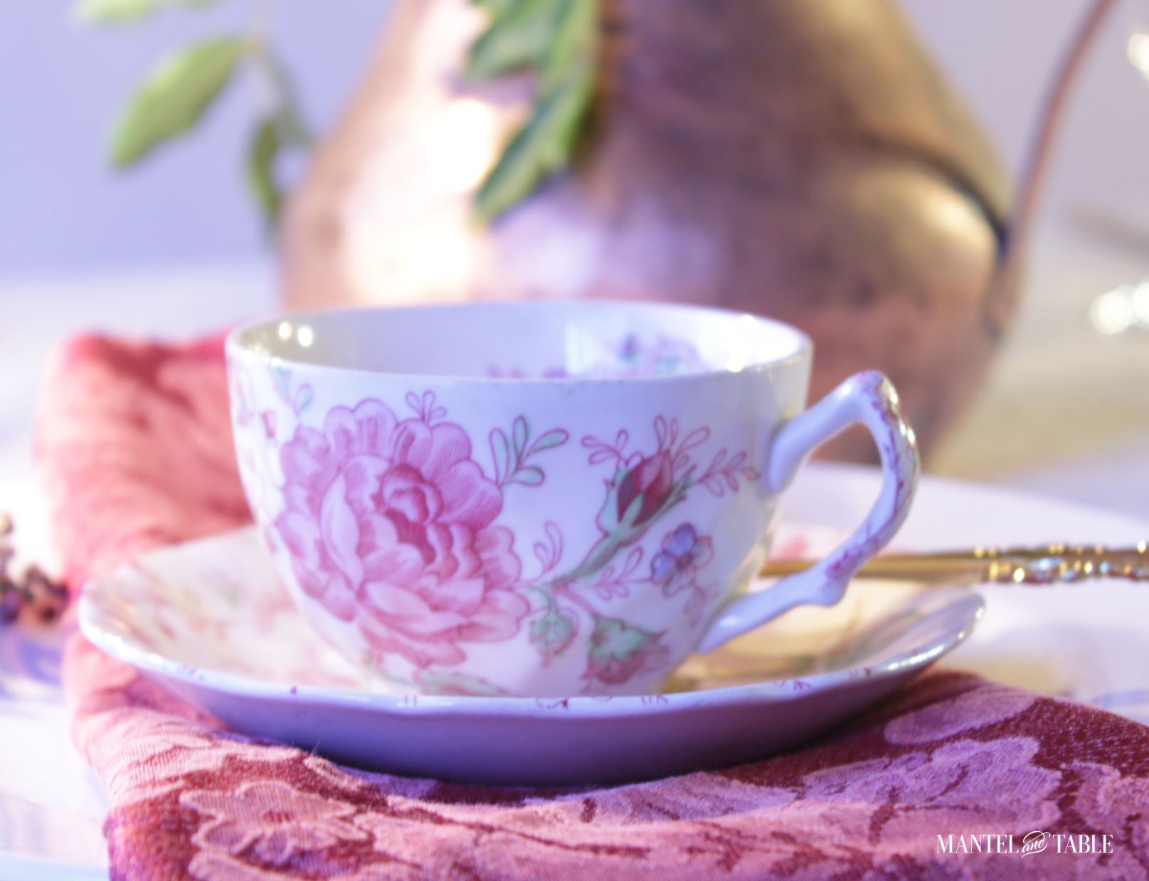 Rose Chintz teacup and saucer closeup on red napkin with copper pitcher behind